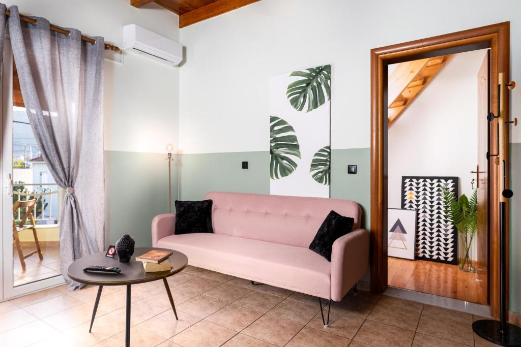 un soggiorno con divano rosa e tavolo di Eagle's Nest City Apartments a Aigio