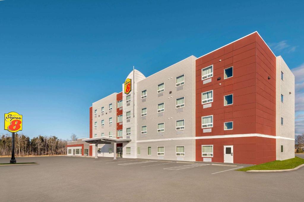 a large red and white building next to a parking lot at Super 8 by Wyndham Thompson in Thompson