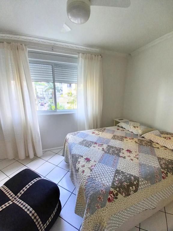 um quarto com uma colcha numa cama e uma janela em Apto 2 Quartos, pertíssimo da Beira-Mar e Ponte HL em Florianópolis