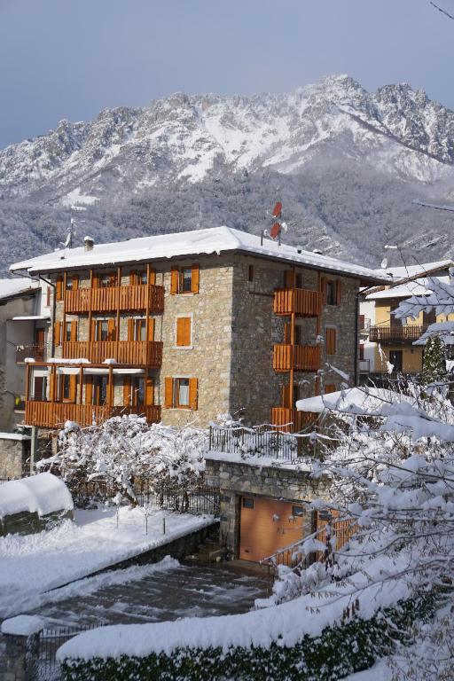 a building in the snow with a river in front at B&B Da Pieri in San Giovanni Bianco