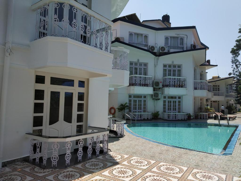 a building with a swimming pool in front of a building at Sunset Beach Resort in Candolim