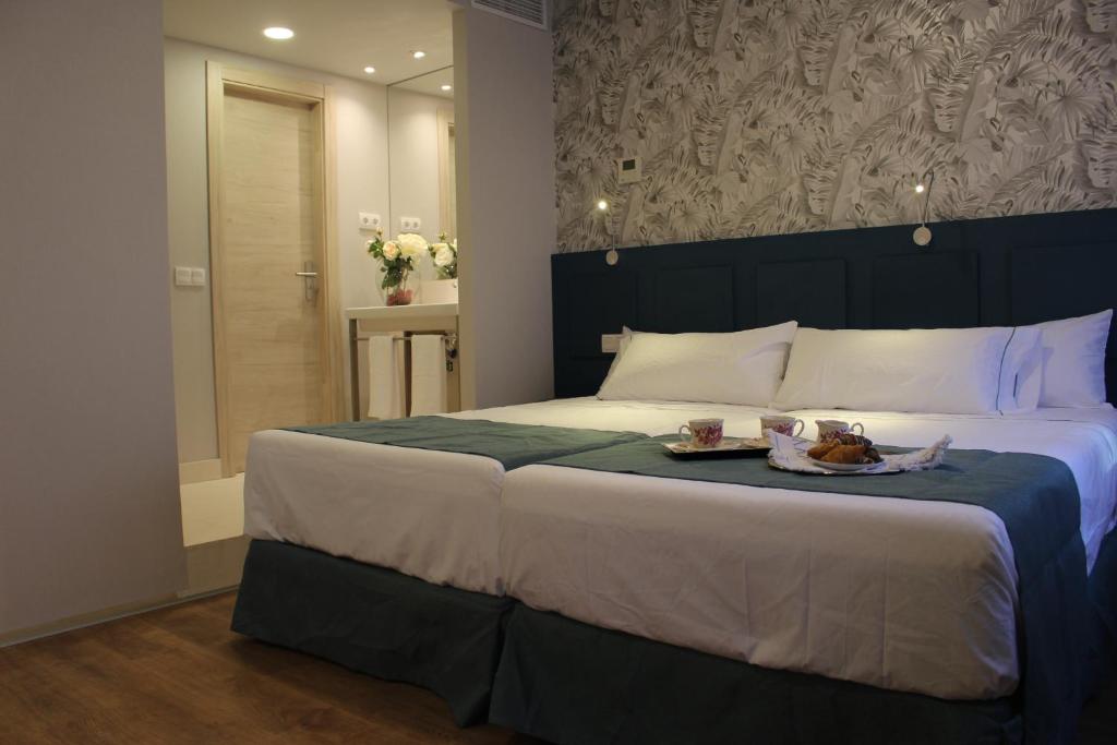 a bedroom with a large bed with a tray of food on it at Modo Hotel Apartamento in Parla