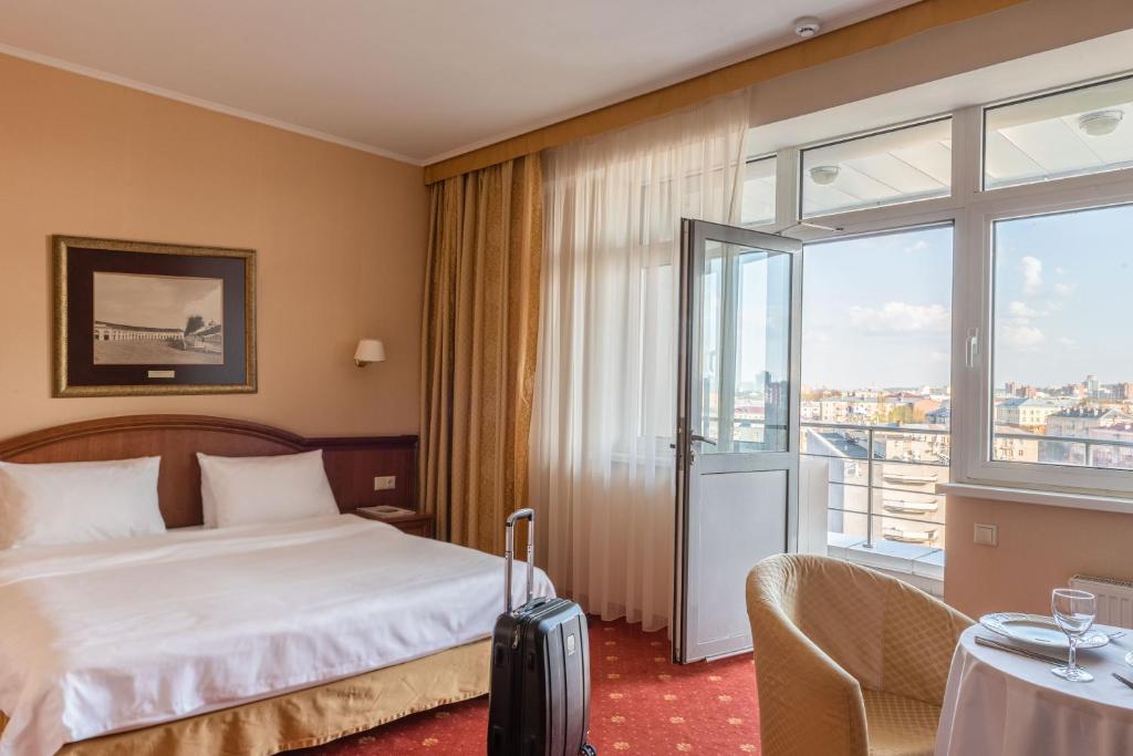 ペトロザヴォーツクにあるCosmos Petrozavodsk Hotelのベッドと大きな窓が備わるホテルルームです。