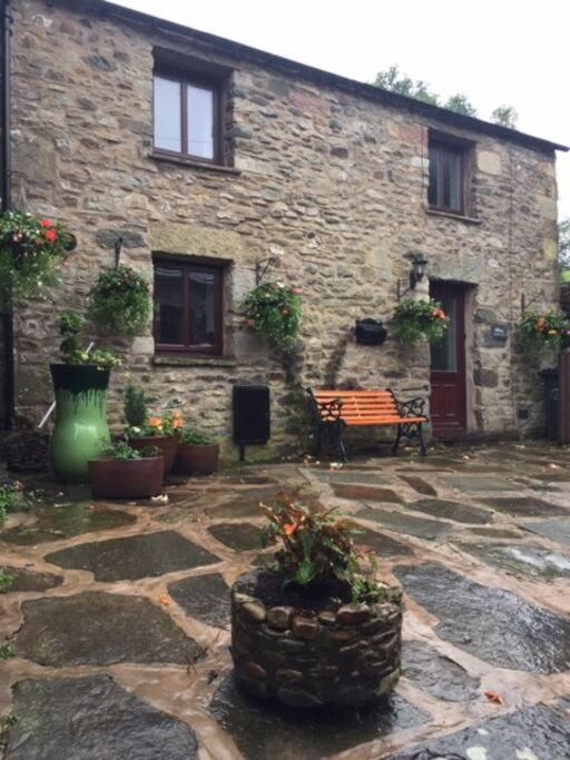 a stone building with a bench and plants in front of it at Dalesway cottage in Sedbergh