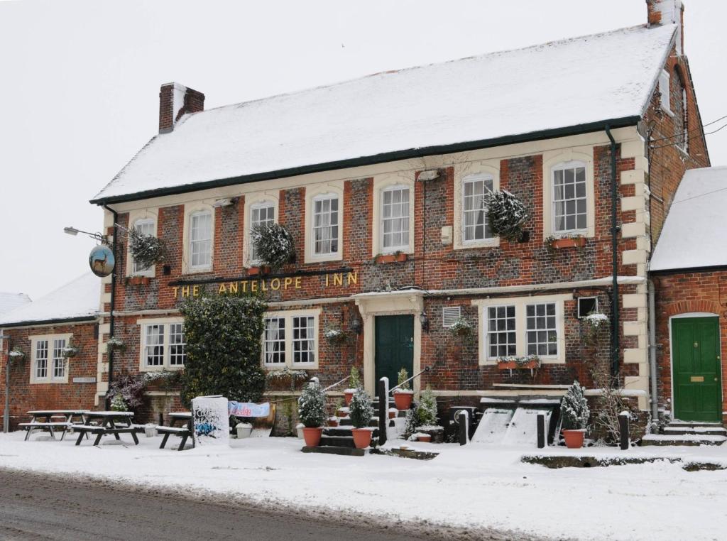 an old brick building with snow on the ground at The Antelope at Upavon in Upavon