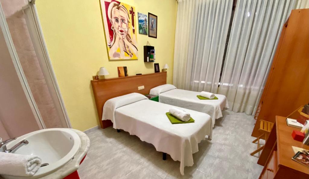 um quarto de hospital com duas camas e um lavatório em Hostal Alvarez em León