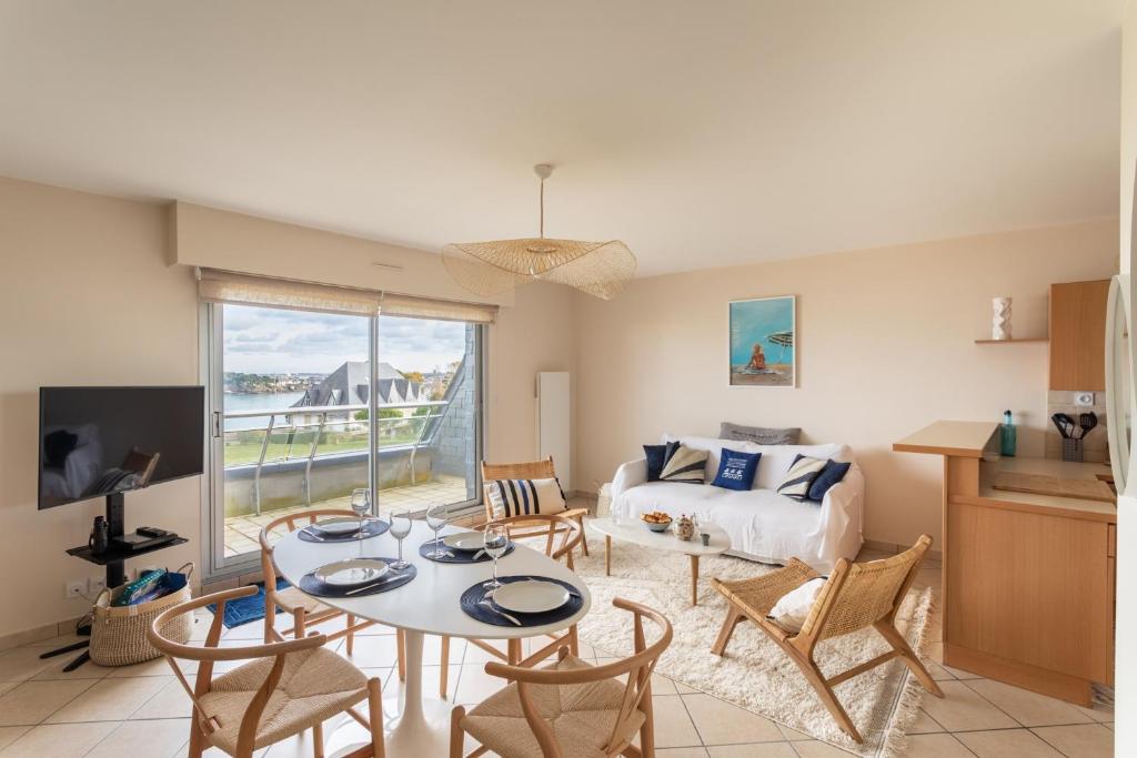 a living room with a couch and a table and chairs at HEOL - appartement 2 chambres - vue mer et parking in Dinard