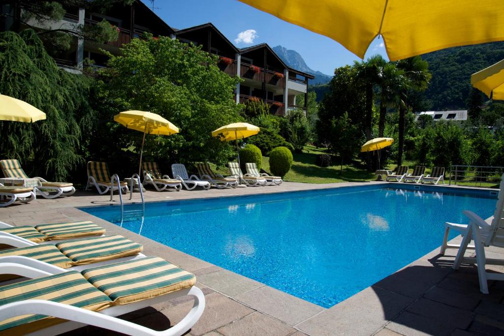 a swimming pool with lounge chairs and umbrellas at Hotel Tannerhof in Merano