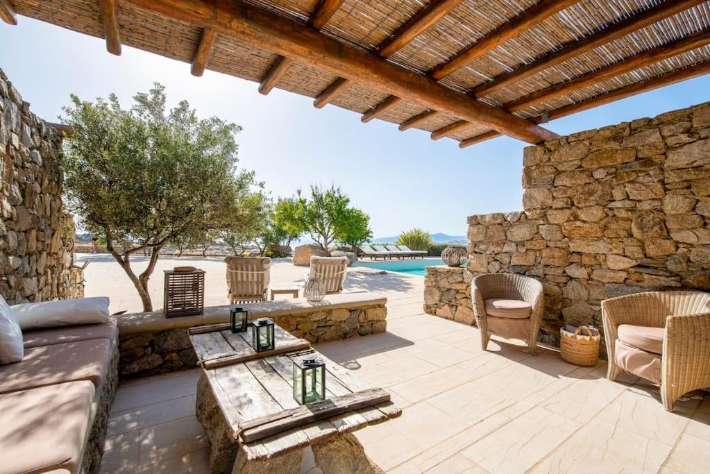 a patio with a couch and chairs and a stone wall at Cave Suite by LLB Villas - Sea & Sunset View in Mýkonos City