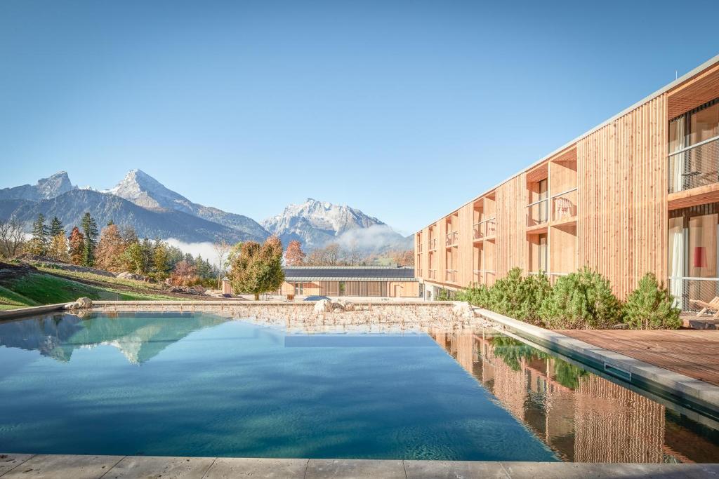 a swimming pool in front of a building with mountains in the background at Kulturhof Stanggass in Bischofswiesen