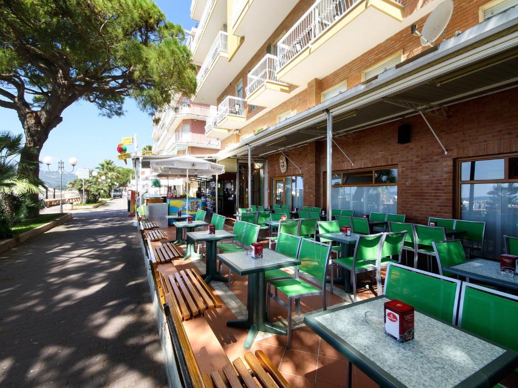 una fila de mesas verdes y sillas fuera de un edificio en Albergo Anita, en San Bartolomeo al Mare