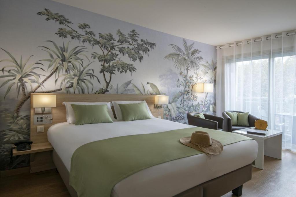 a hotel room with a large bed with a hat on it at Hotel Chambord in Menton