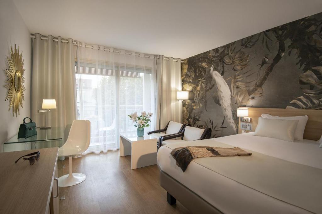 a hotel room with a bed and a desk and a window at Hotel Chambord in Menton