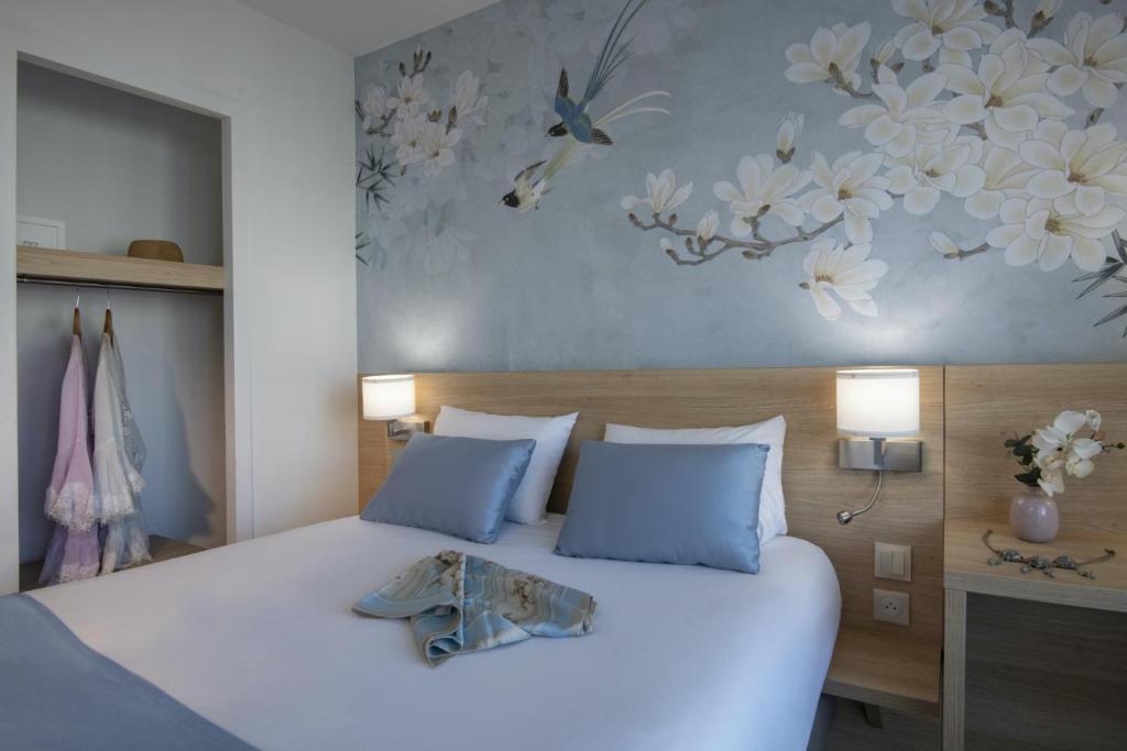 a bedroom with a large white bed with flowers on the wall at Hotel Chambord in Menton