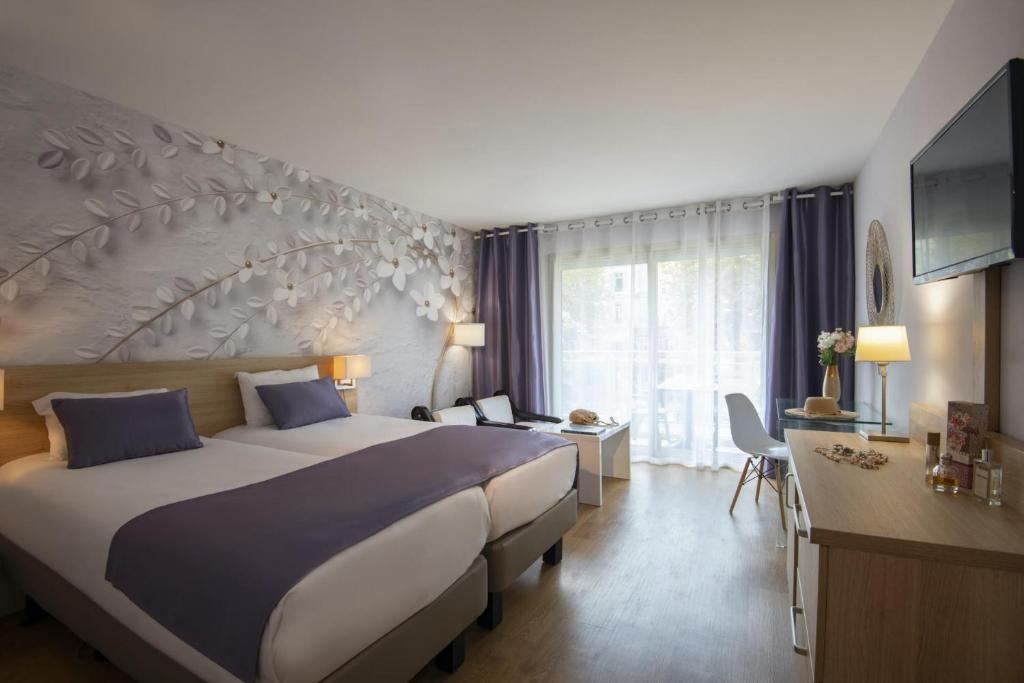 a hotel room with a large bed and a desk at Hotel Chambord in Menton