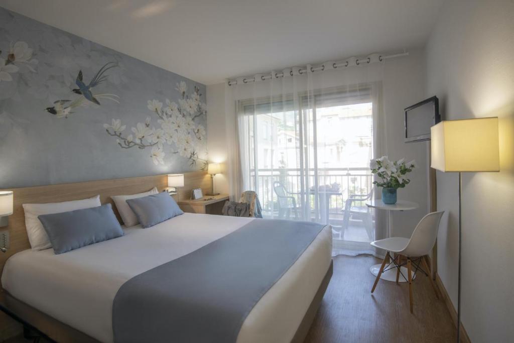 a bedroom with a large bed and a balcony at Hotel Chambord in Menton