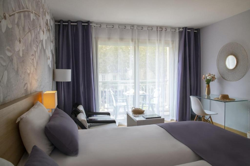 a hotel room with a bed and a large window at Hotel Chambord in Menton