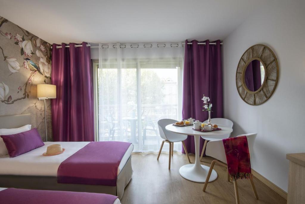 a bedroom with a bed and a table and a window at Hotel Chambord in Menton