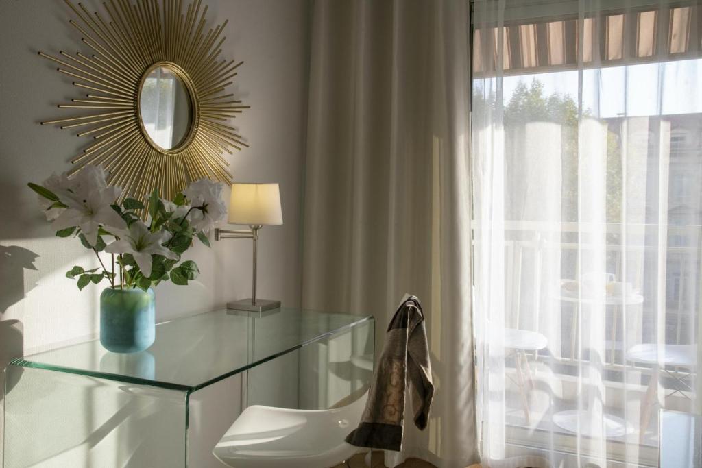 a dressing table with a mirror and a vase of flowers at Hotel Chambord in Menton
