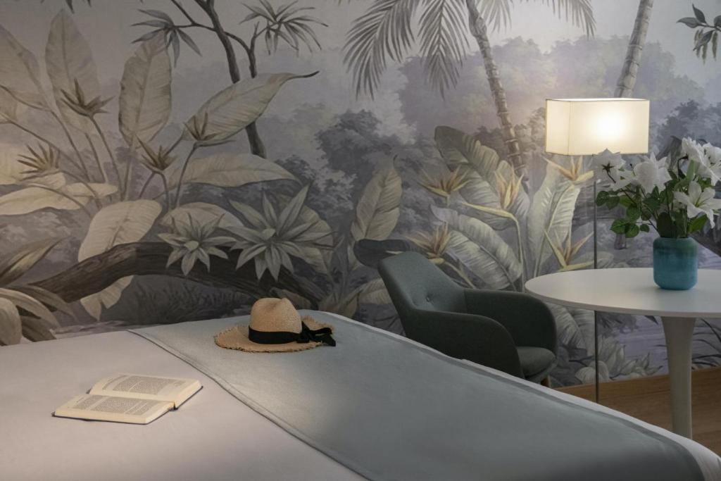 a room with a wall mural with a hat on a table at Hotel Chambord in Menton