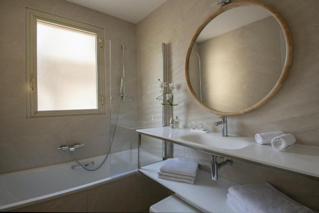 a bathroom with a sink and a mirror and a tub at Hotel Chambord in Menton