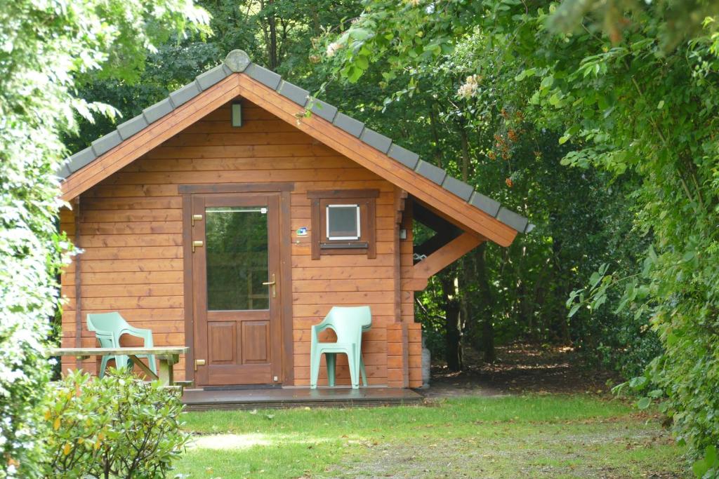 a small cabin with two chairs and a door at Blokhut Camping Alkenhaer in Appelscha