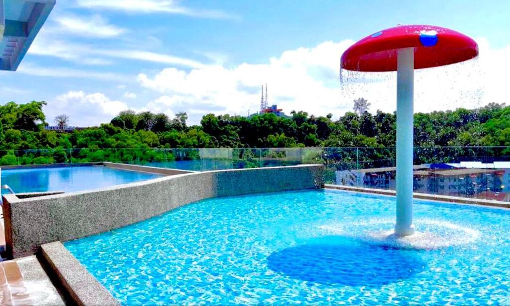 een zwembad met een rode parasol in het water bij Bunga Homestay Sea View in Kuala Terengganu