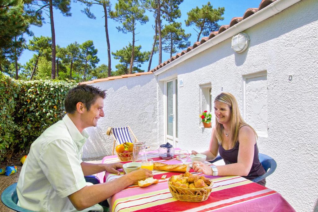 a man and woman sitting at a table with food at Village Club La Grande Baie in La Palmyre
