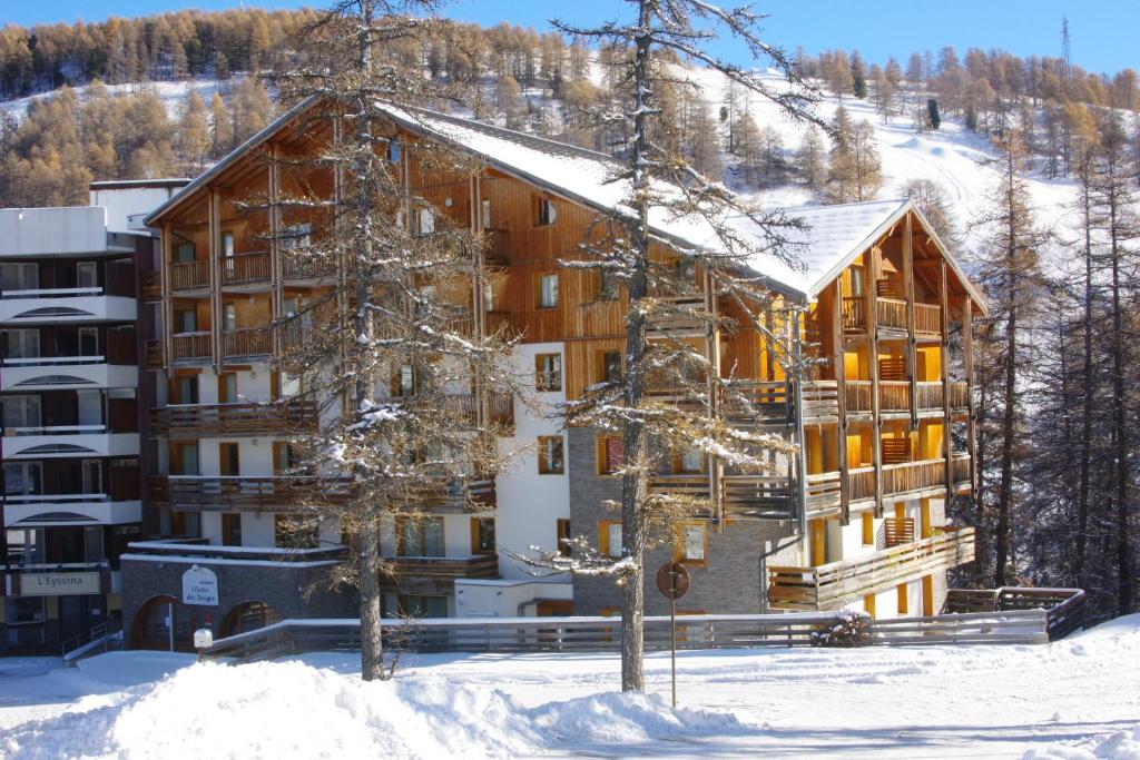 un grand bâtiment en bois dans la neige avec des arbres dans l'établissement Spacieux et Fonctionnel dans Ecrin des Neiges, à Vars