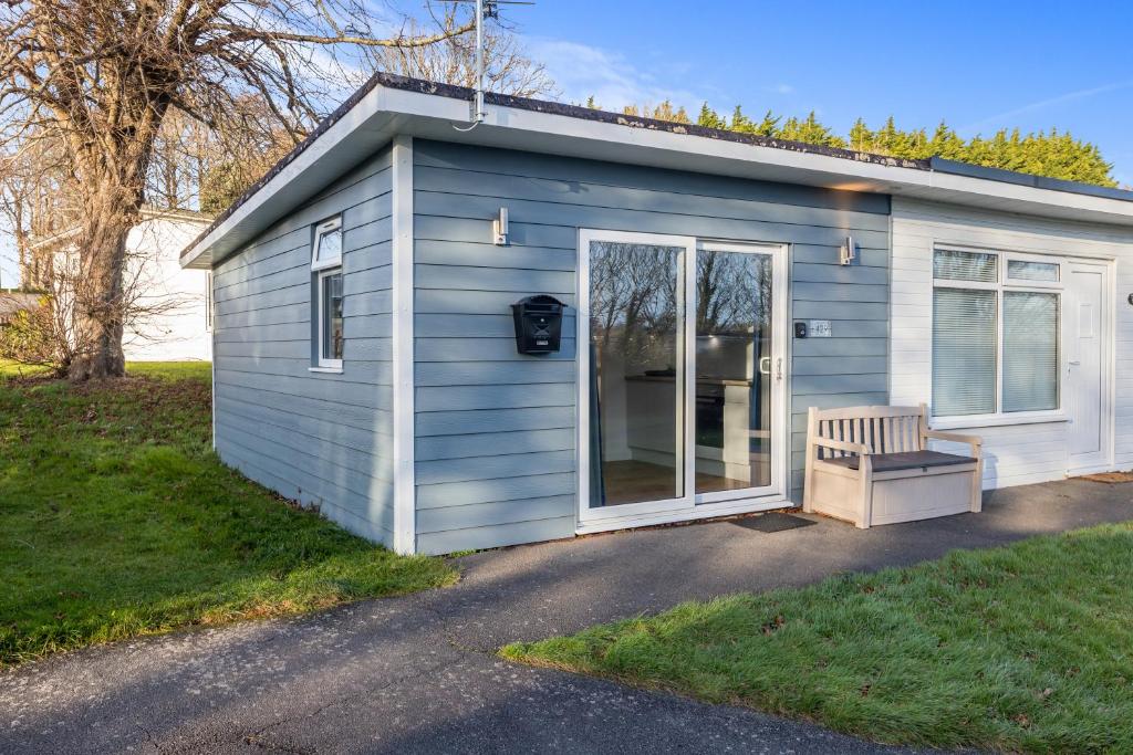 uma pequena casa azul com um banco no quintal em 429 Norton Park em Dartmouth