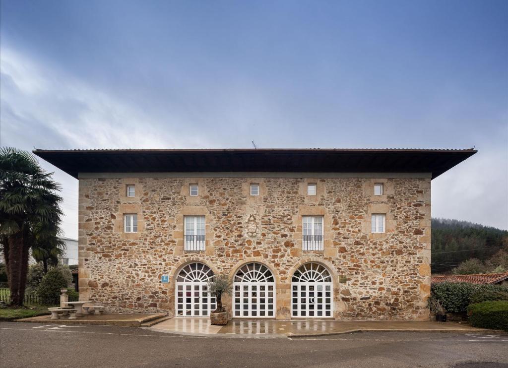 un gran edificio de piedra con techo negro en EtxeAundi Hotel Boutique, en Oñate