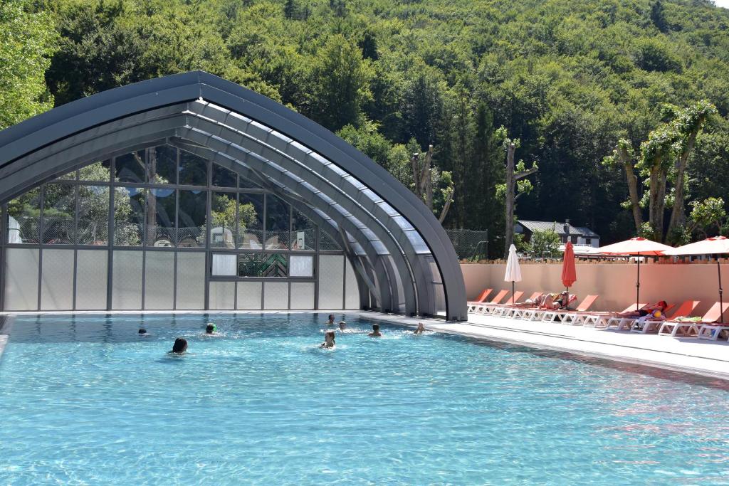 a group of people swimming in a swimming pool at Hôtel Domaine du Lac Chambon in Murol