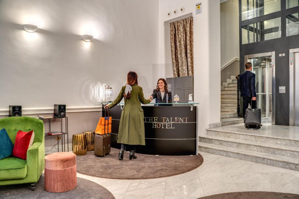a woman standing at a counter in a hotel lobby at The Talent Hotel in Rome