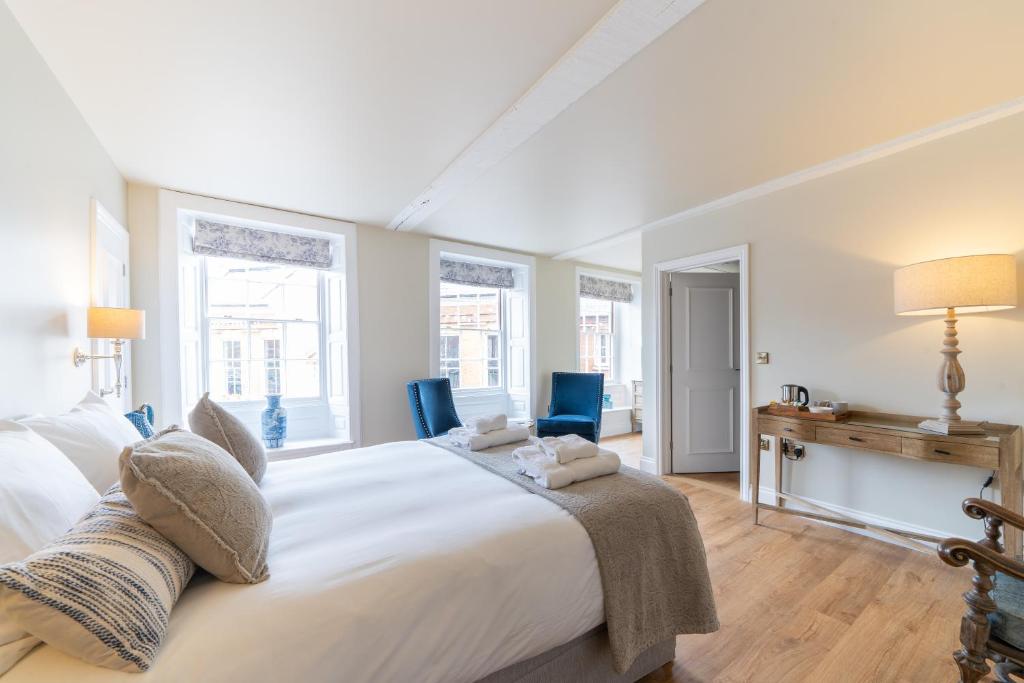 a bedroom with a large white bed and two blue chairs at The Ironmongers Boutique accommodation in Aylsham