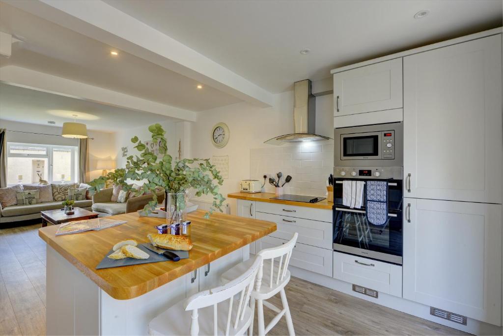 a kitchen with white cabinets and a wooden counter top at Tunlaw Cottage in Kineton