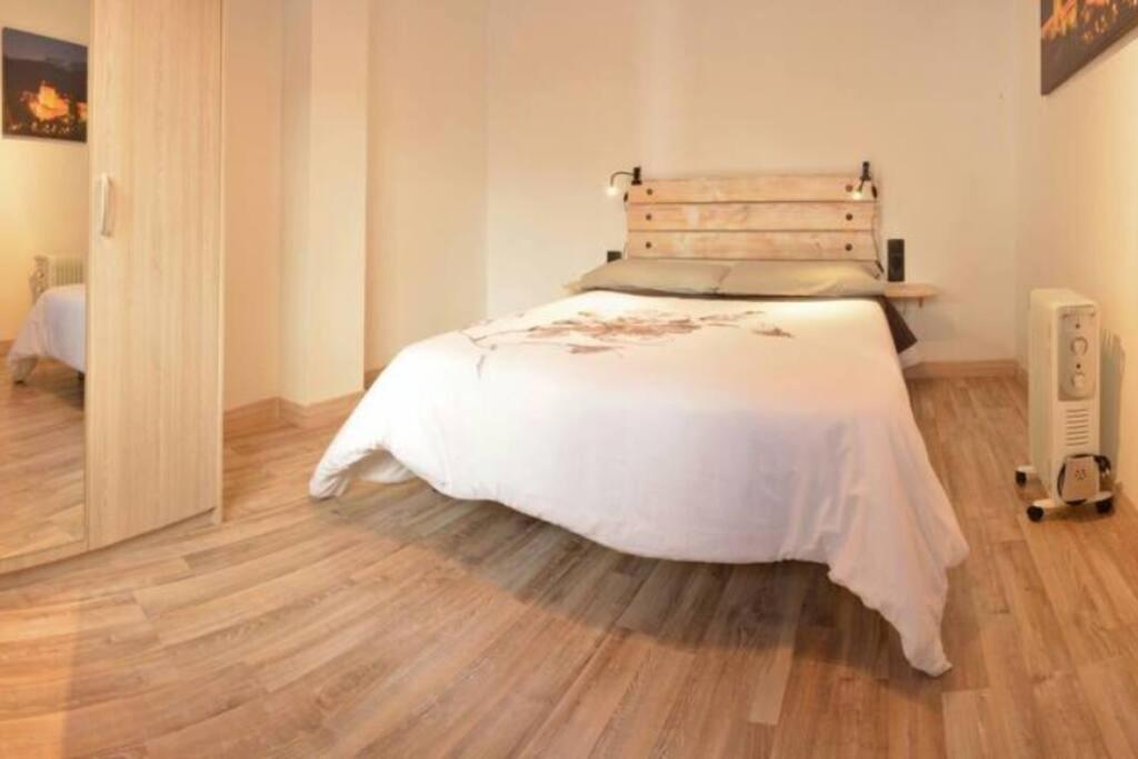 a bedroom with a white bed and a wooden floor at BONITO AP CENTRICO PATIO WIFI PARKING GRATIS. in Granada