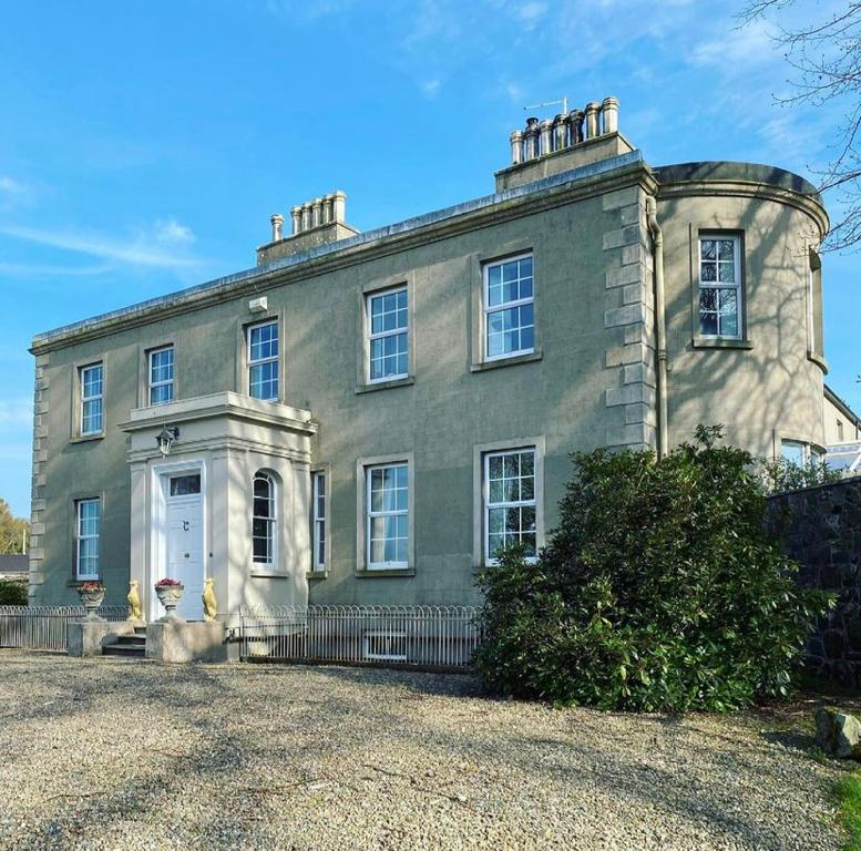 une grande maison grise avec une clôture devant elle dans l'établissement Little Woodbank, à Portadown