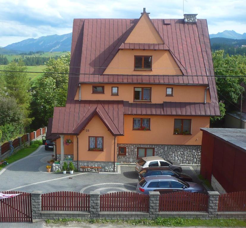 une maison avec un toit rouge et des voitures garées dans un parking dans l'établissement Smyrecek-centrum Bukowiny, à Bukowina Tatrzańska