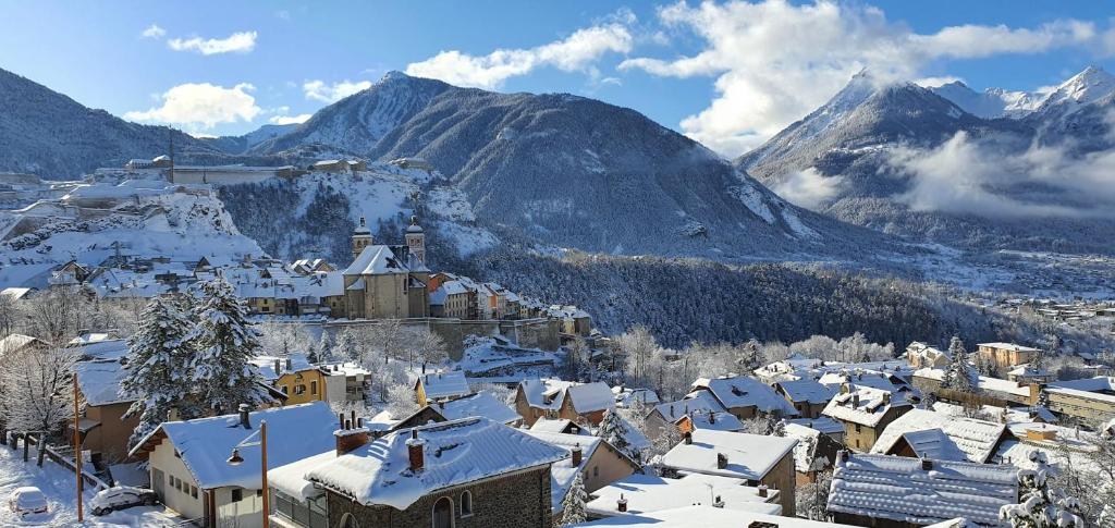 une ville couverte de neige devant une montagne dans l'établissement Apt With Panoramic View Near Vauban City, à Briançon