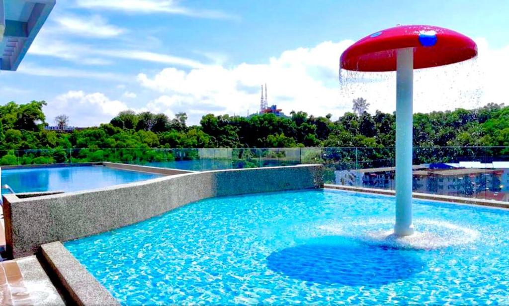 a swimming pool with a red umbrella in the water at Bunga Homestay Icon Residence KUALA TERENGGANU in Kuala Terengganu