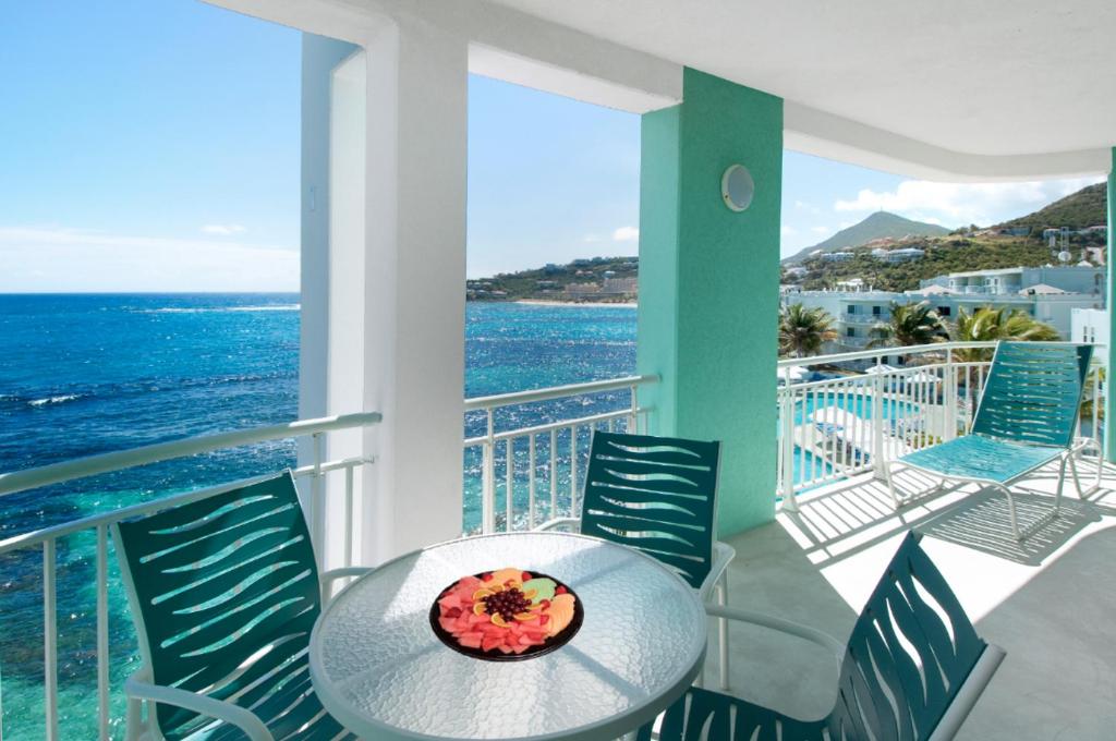 a table and chairs on a balcony with the ocean at Oyster Bay Beach Resort in Dawn Beach
