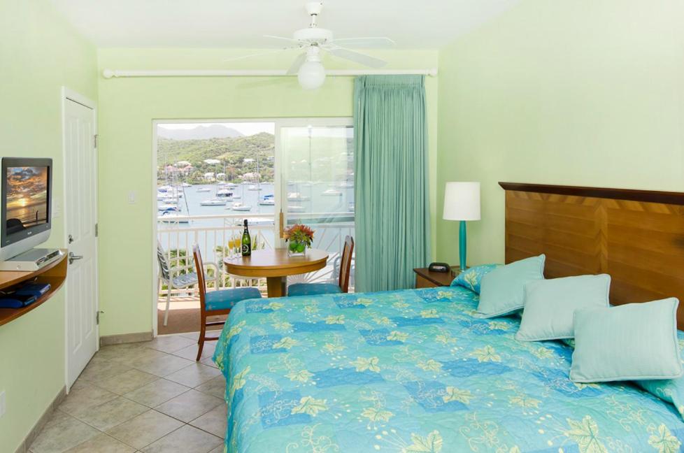 a bedroom with a bed and a table and a balcony at Oyster Bay Beach Resort in Dawn Beach