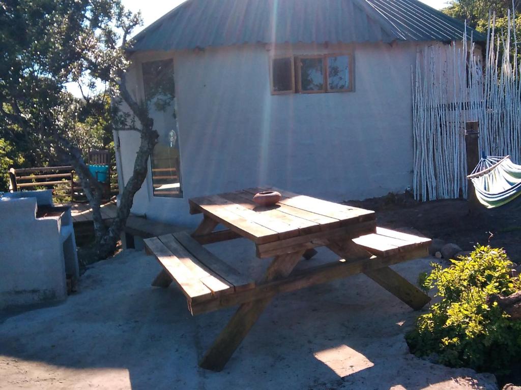 una mesa de picnic frente a un cobertizo blanco en Wildview Self Catering Cottages Coffee Bay, Breakfast & Wi-Fi inc en Coffee Bay