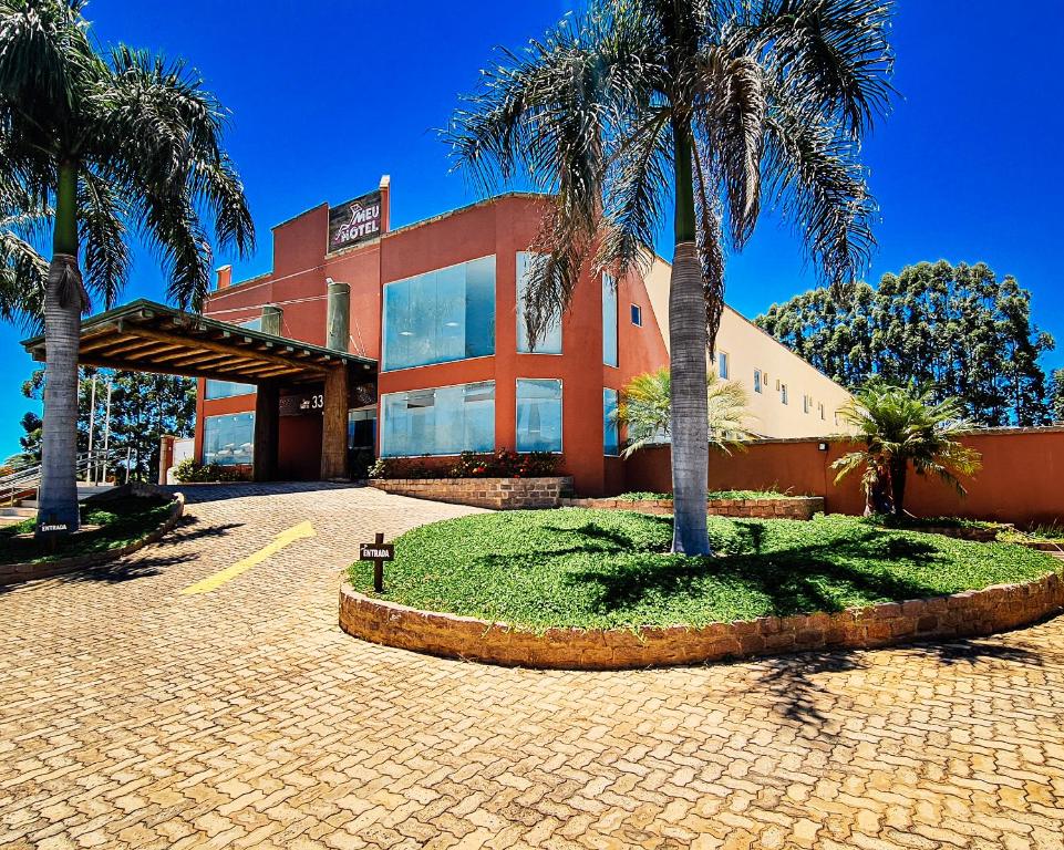 a building with palm trees in front of it at Meu Hotel Garça in Garça