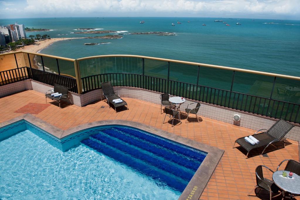 a swimming pool with a view of the ocean at Quality Suites Vila Velha in Vila Velha
