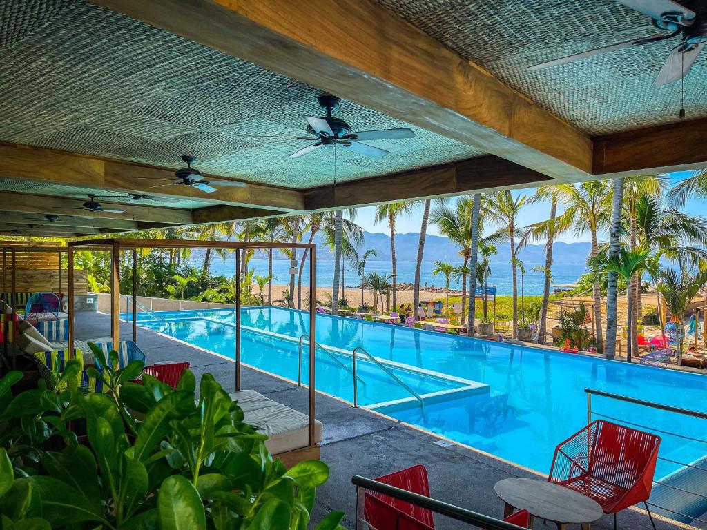 vistas a una piscina con sillas rojas y palmeras en Friendly Fun Vallarta Different Experiences, en Puerto Vallarta