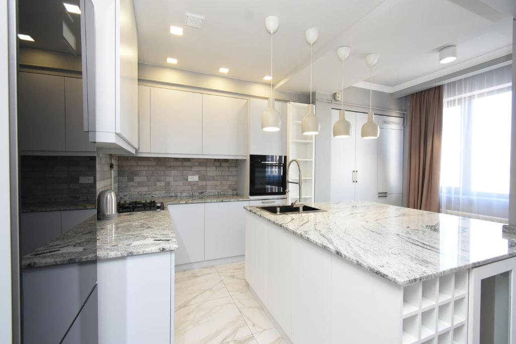 a kitchen with white cabinets and marble counter tops at Luxury apartment in Yerevan, Komitas 36b in Yerevan