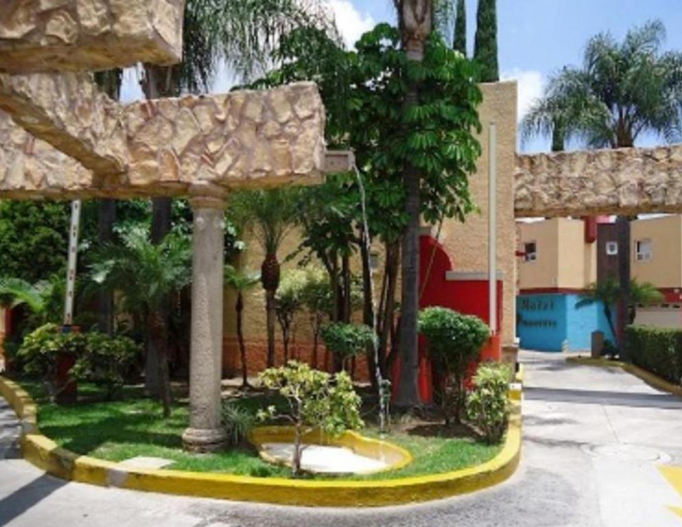un jardín con árboles, un edificio y una calle en Motel Primavera en Guadalajara