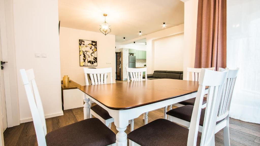 a dining room and living room with a wooden table and chairs at Iancului ApartHotel in Bucharest