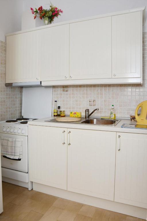 kuchnia z białymi szafkami i zlewem w obiekcie Eirini - LOGGOS APARTMENTS w mieście Longós